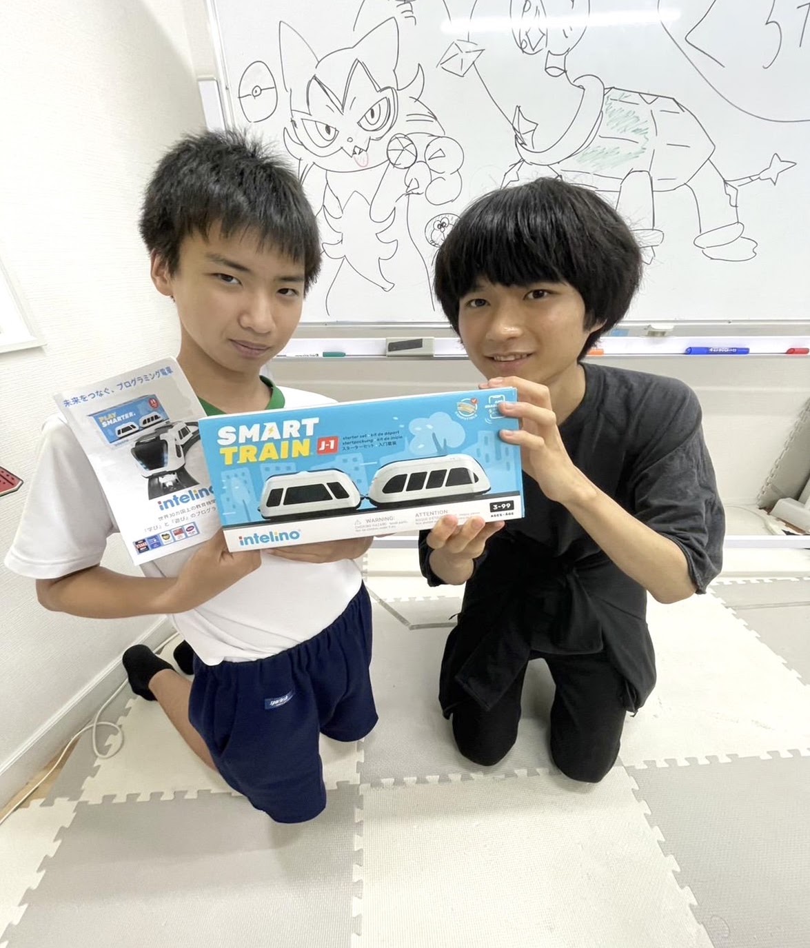スマートトレインの製品箱と資料を持つ体験会の参加者とスタッフ