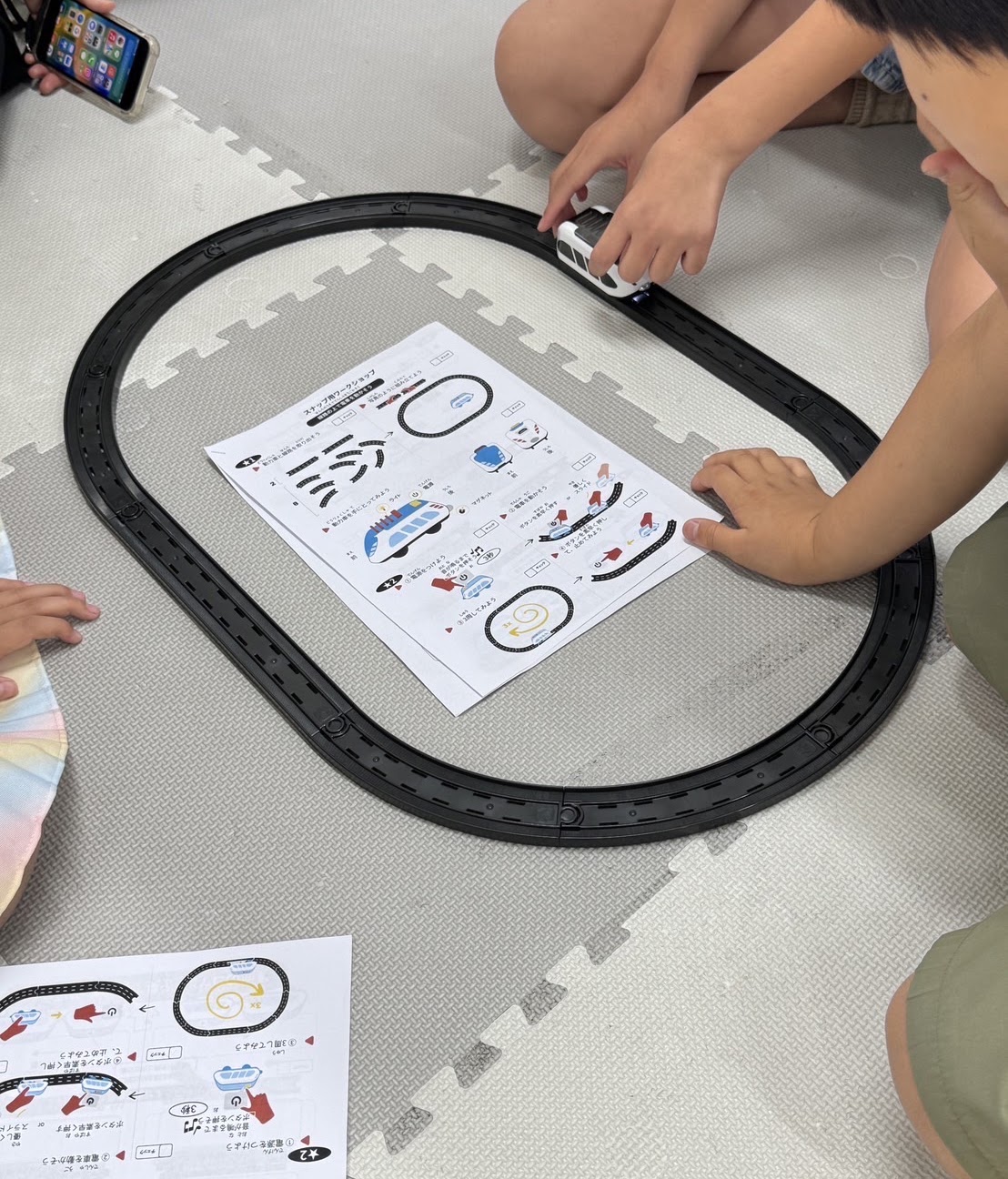 線路上のスマートトレインと学習プリントを使って課題に取り組む参加者