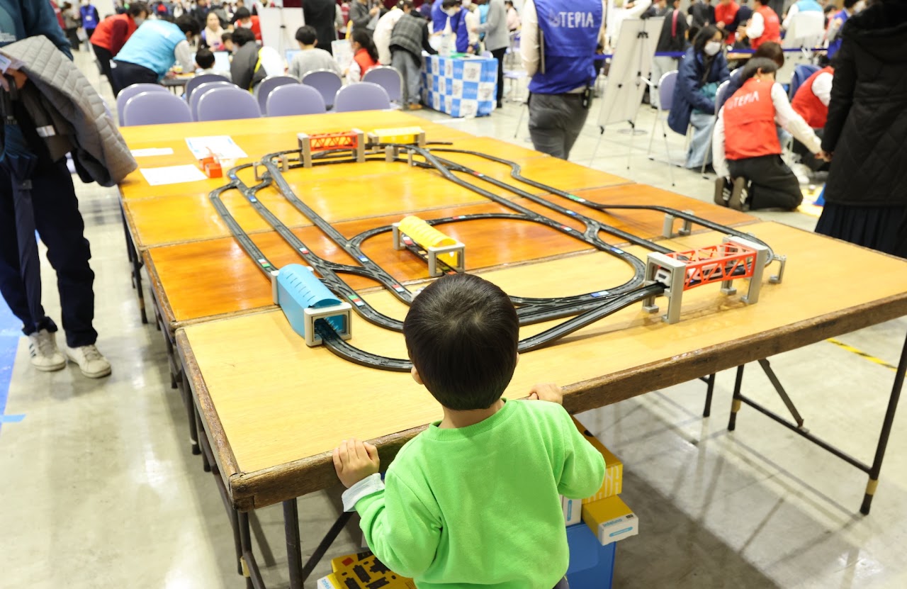 橋やトンネルを組み合わせたスマートトレインの展示コースを見る参加者